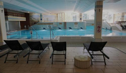 a swimming pool with chairs in front of it at Sylva Apartment inkl TG-Platz im Predigtstuhl Resort in Sankt Englmar