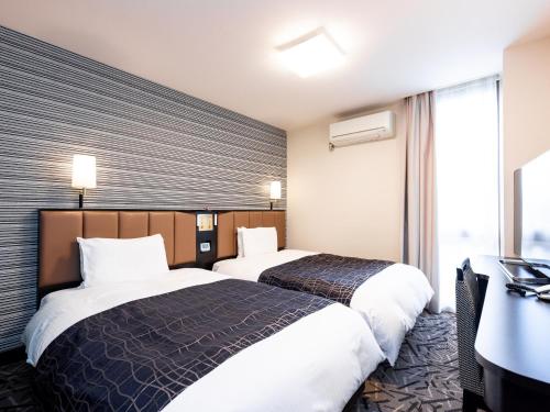 a hotel room with two beds and a desk at APA Hotel Saga Ekimae Chuo in Saga
