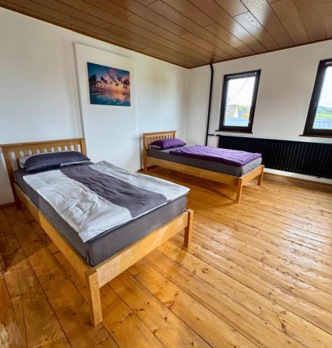 two beds in a room with wooden floors and windows at Appartement 1 