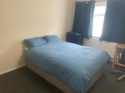 a bedroom with a bed with blue sheets and a window at Payton Mews in Hackington