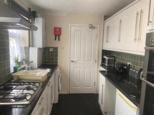 a kitchen with white cabinets and a sink and a stove at Payton Mews in Hackington