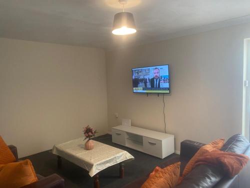 a living room with a couch and a tv on the wall at Payton Mews in Hackington