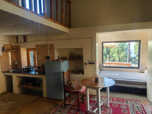 a kitchen with a refrigerator and a table and a window at Astitva Binsar in Hawālbāgh