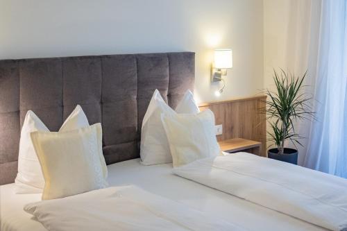 a bedroom with a white bed with white pillows at Hotel Drescher in Mörbisch am See