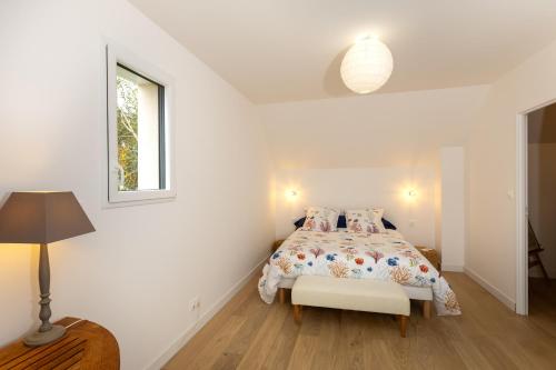 a white bedroom with a bed and a lamp at Villa Les Charmettes in Saint-Lunaire