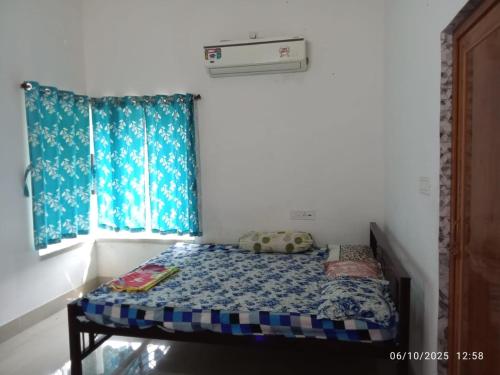 a small bed in a room with blue curtains at Swapno Chhobi in Shānti Niketan