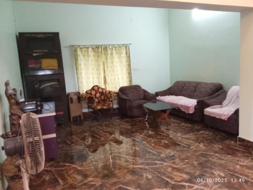 a living room with couches and chairs and a marble floor at Swapno Chhobi in Shānti Niketan