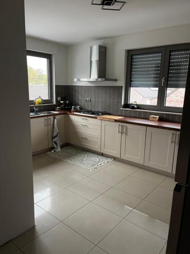 a kitchen with white cabinets and a tile floor at Duplex appartement met 3 slaapkamers in Genk