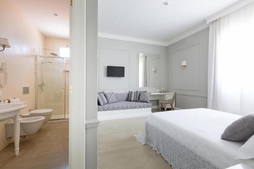 a white bedroom with a bed and a bathroom at Palazzo Fasti in Casarano