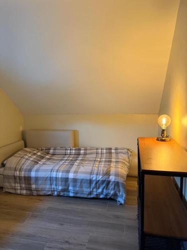 a bedroom with a bed and a table with a lamp at Duplex appartement 'De Wijers' met 3 slaapkamers in Genk