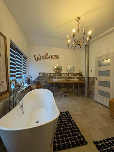 a bathroom with a tub and a wellness sign on the wall at FichtelLOFT Retreat-Design Loft nahe Bayreuth in Goldkronach