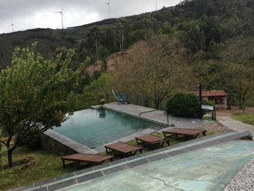 a swimming pool with picnic tables in front of a hill at Pátio do Xisto in Gondramaz