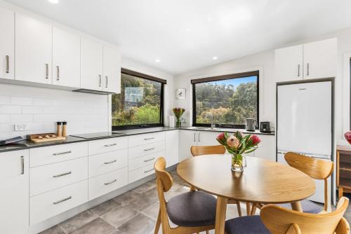 a kitchen with white cabinets and a table with a vase of flowers at Tranquil Getaway in Tinderbox in Tinderbox