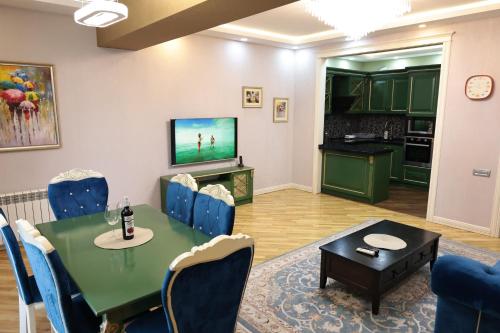 una sala da pranzo con un tavolo verde e sedie blu di Azur 11 a Baku