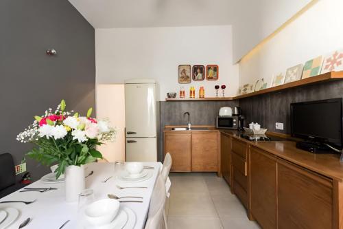 バレッタにあるMagic romantic escape in the heart of Vallettaの花瓶に花が飾られたテーブルのあるキッチン