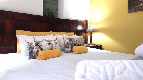 a bedroom with a bed with white sheets and pillows at The Anvil Rest Cottage in Calitzdorp