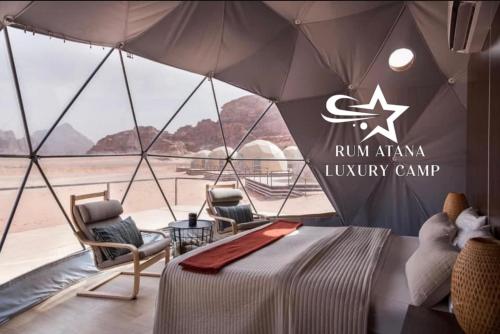 a room with a bed and chairs and an umbrella at WADI RUM ATANO lUXURY CAMP in Wadi Rum