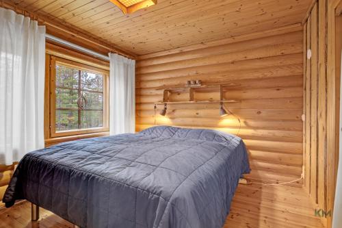 a bedroom with a bed in a wooden wall at Villa Aurora - Valkea Homes in Pelkosenniemi