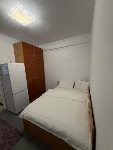 Un dormitorio pequeño con una cama y un refrigerador. en Urban Confort Studio, en Popeşti-Leordeni