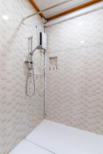 a shower in a bathroom with white tiles at Maafolhey Han'dhaan - Ukulhas in Ukulhas