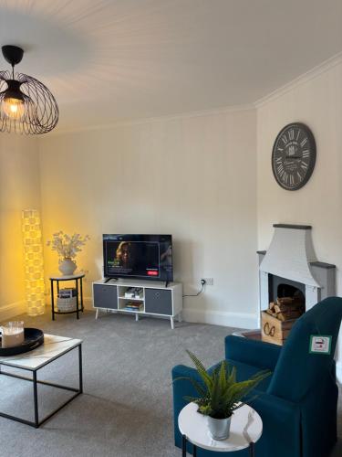 a living room with a blue couch and a tv at Cosy 2 Bed Maisonette near Heathrow & Windsor in Staines