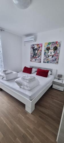 een groot wit bed in een witte kamer met rode kussens bij Penthouse Dream Vista in Čižići