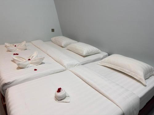 2 Betten mit weißen Kissen und Blumen darauf in der Unterkunft Bongga Village Resort in Semporna