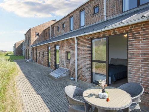 a brick building with a patio with a table and chairs at Apartment with shared kitchen in Holiday park in Ulfborg