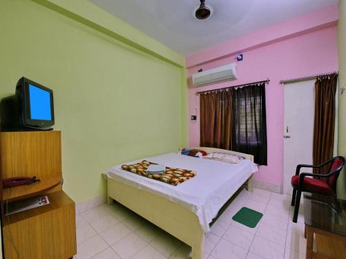 a bedroom with a bed and a tv in it at Hotel Cosy Inn in Digha