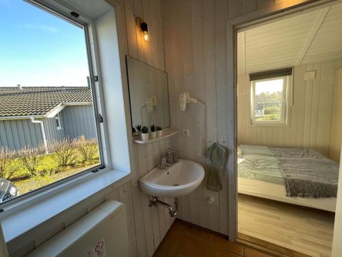 a bathroom with a sink and a window and a bed at Ferienhaus Lykkehus Grömitz in Grömitz