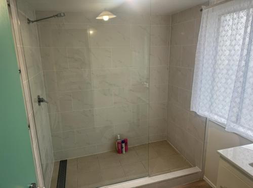 a bathroom with a shower with a glass door at CBD Holiday Home in Mackay