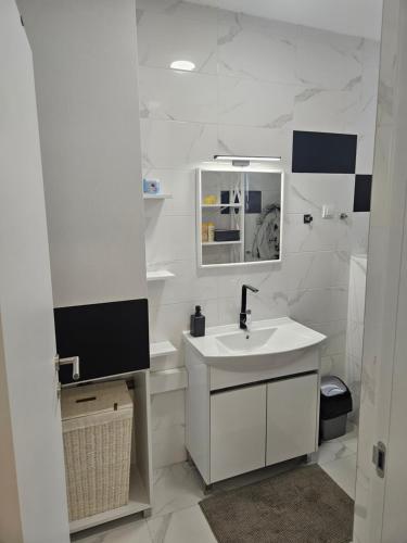 a white bathroom with a sink and a mirror at Miss Extra LuX in Mladenovac