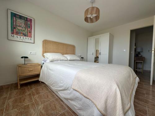 a bedroom with a large white bed and a night stand at Apartamento Balea - San Vicente do Mar in Balea