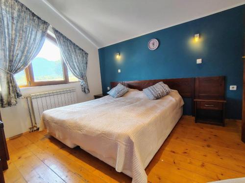 ein Schlafzimmer mit einem großen Bett und einer blauen Wand in der Unterkunft Fairytale Cottage in Redenka in Raslog