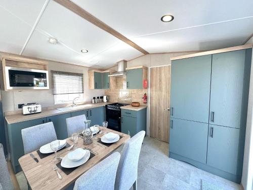 a kitchen with a wooden table and blue cabinets at Modern Caravan 2025 with Decking in Morecambe