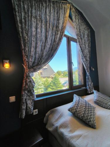 a bedroom with a window and a bed with pillows at Fairytale Cottage in Redenka in Razlog