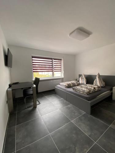 a bedroom with a bed and a desk and a window at Modernes 1-Zimmer Apartment mit Küche und Bad in Merzig