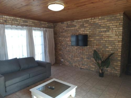 a living room with a couch and a tv on a brick wall at BushWave in Jeffreys Bay