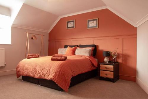 a bedroom with a large bed with orange walls at Our Home from Home in the heart of Abergavenny in Abergavenny