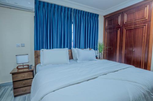 una camera da letto con un grande letto con tende blu di KAJAZZ properties a East Legon