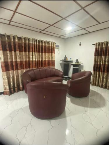 a living room with two brown chairs and a table at Heart Whispering in Kandy