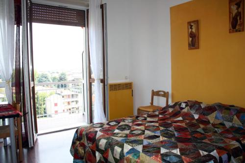 een slaapkamer met een quilt op een bed en een raam bij Easy Arese Apartment in Garbagnate Milanese