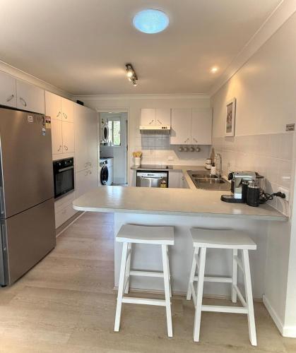 a kitchen with a large counter and two stools at Forster Holiday Home Cozy, Central & Near Beach in Forster