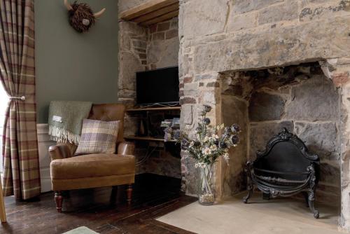 a living room with a stone fireplace with a chair and a television at Rose Apartment in Edinburgh