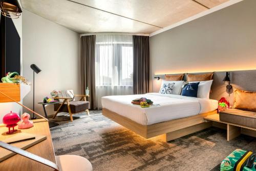 a hotel room with a bed and a couch at Moxy Hamburg - Finkenwerder in Hamburg