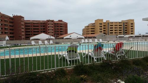 un grupo de sillas sentadas junto a una piscina en La Serena Mini Departamento, en La Serena