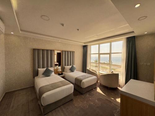 a hotel room with two beds and a large window at Rose Land Hotel in Umm Lujj
