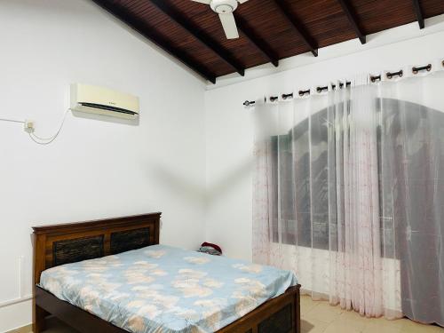 a bedroom with a bed and a window with a curtain at Kashmir villa in Galle