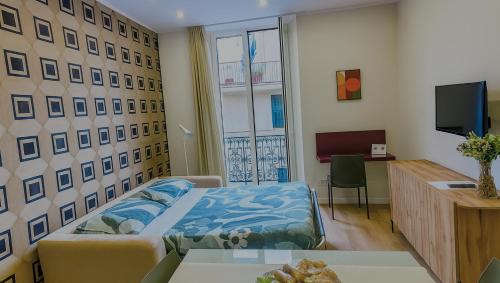 a bedroom with a bed and a desk and a window at Sul Corso Sanremo in Sanremo
