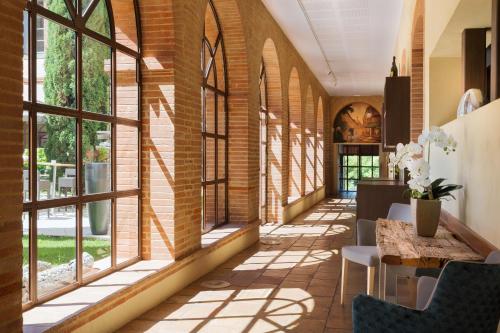 - un couloir avec des fenêtres, une table et des chaises dans l'établissement Abbaye des Capucins Spa & Resort, à Montauban